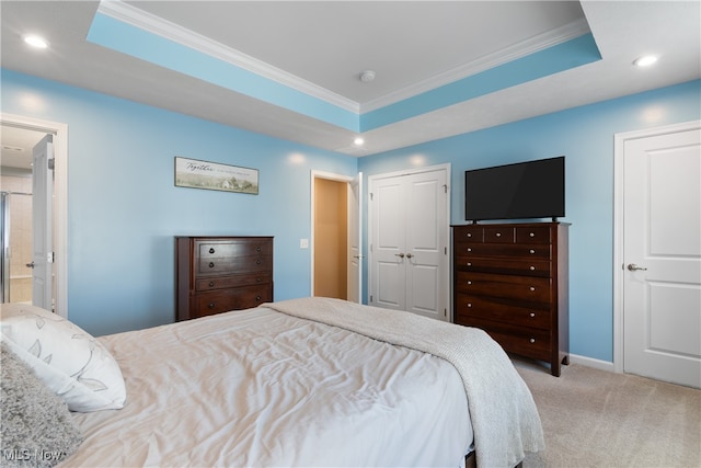 carpeted bedroom with a raised ceiling, ornamental molding, and connected bathroom