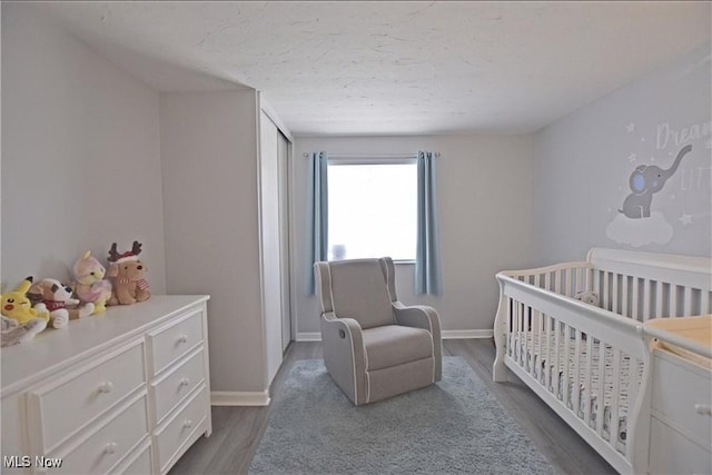 bedroom with dark wood-type flooring, a nursery area, and a textured ceiling