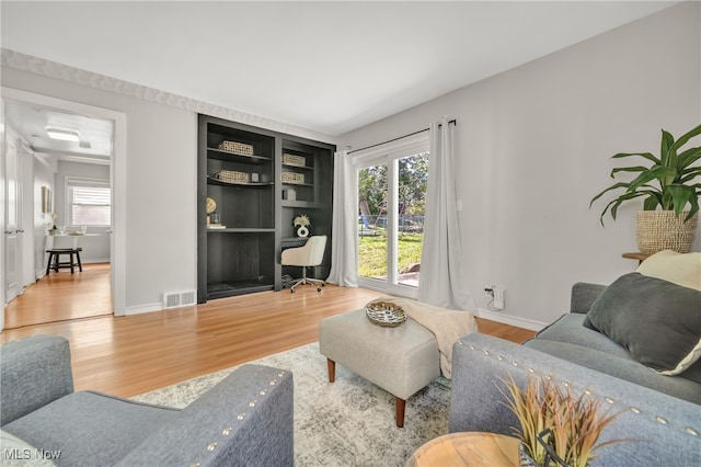 living room featuring hardwood / wood-style flooring, built in features, and a wealth of natural light