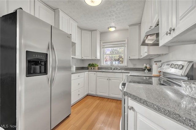 kitchen featuring appliances with stainless steel finishes, light wood-type flooring, a textured ceiling, sink, and white cabinets