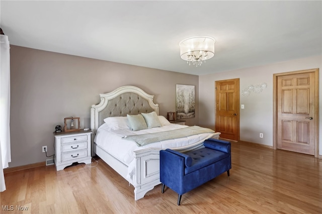 bedroom with light hardwood / wood-style floors and a chandelier