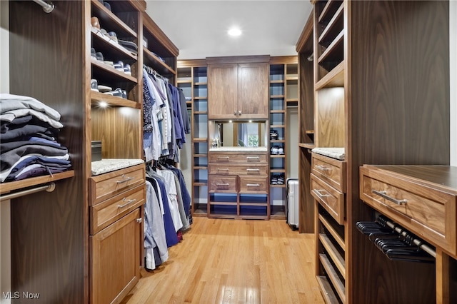 walk in closet with light hardwood / wood-style flooring