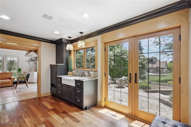 entryway featuring light wood-type flooring, french doors, crown molding, and plenty of natural light