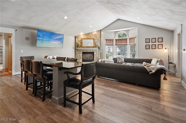 dining area with a fireplace, hardwood / wood-style flooring, and vaulted ceiling