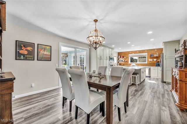 dining area featuring light wood-type flooring, plenty of natural light, and an inviting chandelier