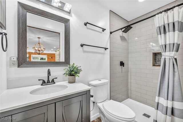 bathroom with a shower with curtain, vanity, a chandelier, and toilet