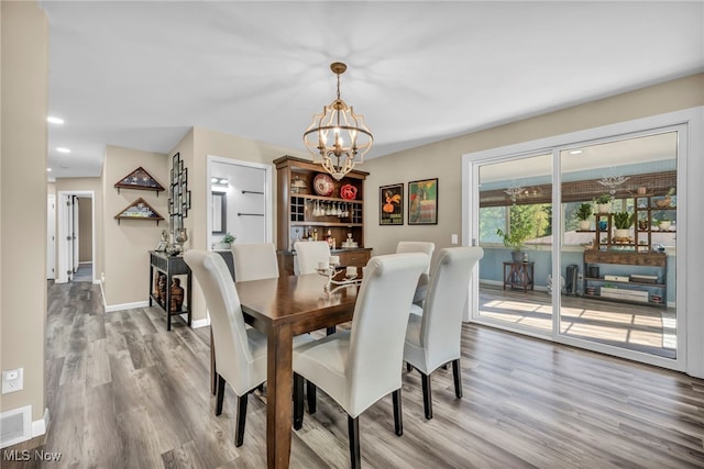 dining area featuring hardwood / wood-style floors and an inviting chandelier