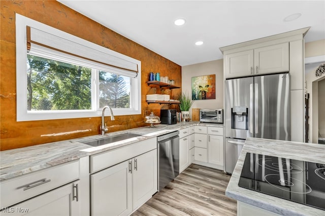 kitchen featuring white cabinets, sink, light hardwood / wood-style flooring, appliances with stainless steel finishes, and light stone countertops