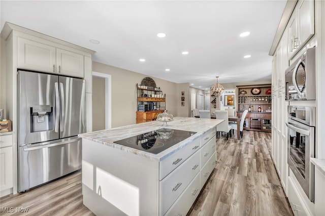 kitchen with white cabinets, appliances with stainless steel finishes, light hardwood / wood-style floors, and a kitchen island