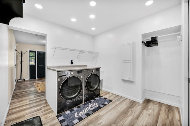 laundry room with washer and clothes dryer and light hardwood / wood-style flooring