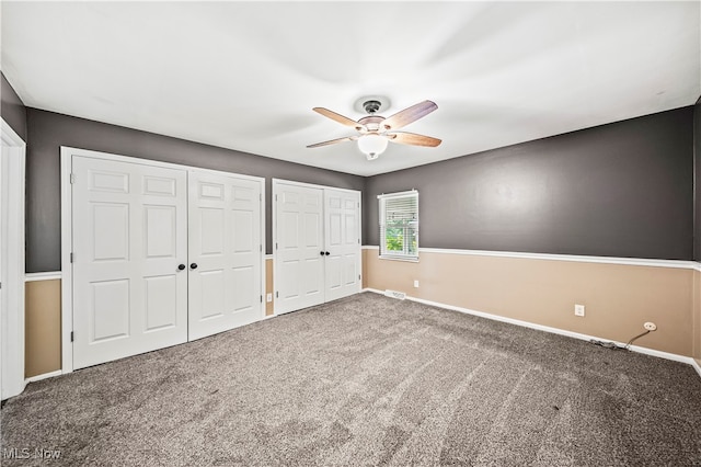 unfurnished bedroom featuring multiple closets, carpet, and ceiling fan