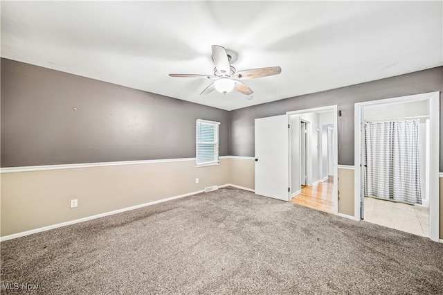 unfurnished bedroom featuring ceiling fan, light carpet, and ensuite bathroom