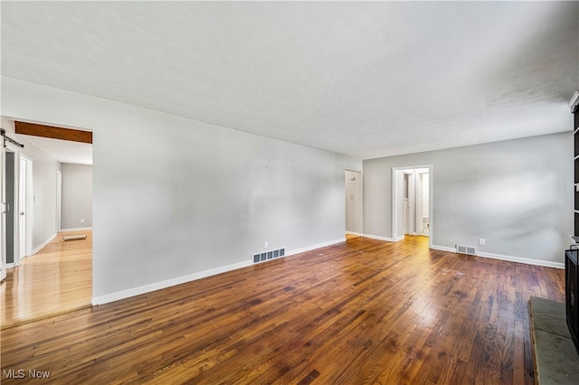 spare room with a barn door and hardwood / wood-style floors