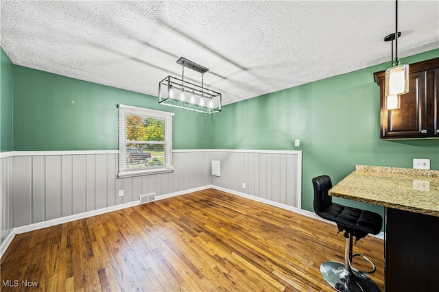 unfurnished dining area featuring hardwood / wood-style floors and a textured ceiling