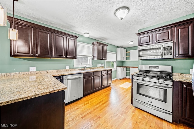 kitchen with dark brown cabinets, hanging light fixtures, a textured ceiling, light wood-type flooring, and stainless steel appliances