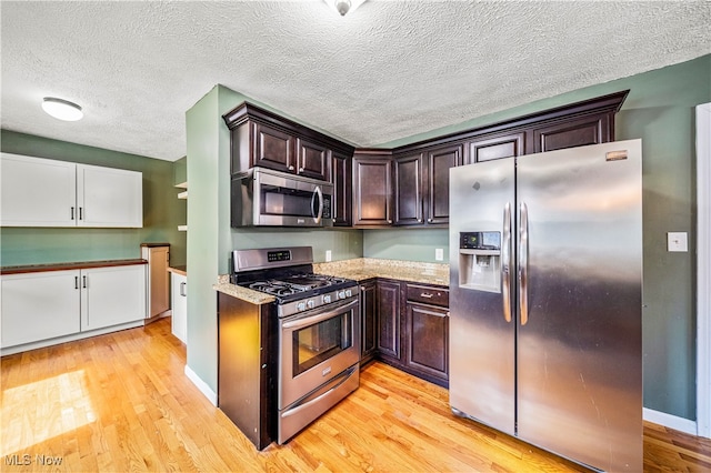 kitchen with stainless steel appliances, dark brown cabinets, light hardwood / wood-style flooring, and a textured ceiling