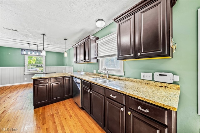 kitchen with a textured ceiling, stainless steel dishwasher, pendant lighting, light hardwood / wood-style floors, and sink