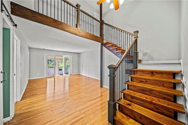 staircase with hardwood / wood-style floors, a barn door, and ceiling fan