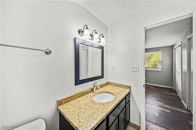 bathroom with vanity, lofted ceiling, hardwood / wood-style floors, and toilet