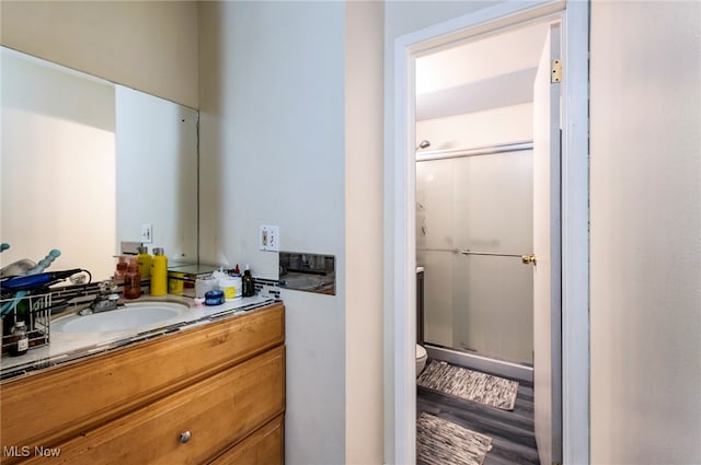 bathroom featuring toilet, a shower with door, vanity, and wood-type flooring