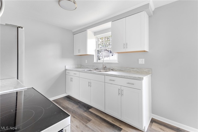 kitchen featuring white cabinets, stove, sink, and hardwood / wood-style floors