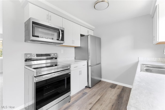 kitchen featuring white cabinets, stainless steel appliances, sink, and light wood-type flooring