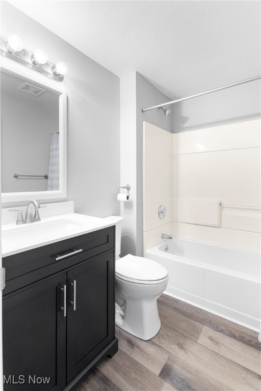 full bathroom featuring hardwood / wood-style flooring, toilet, shower / tub combo, vanity, and a textured ceiling