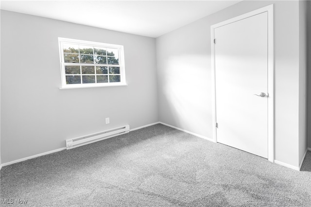 carpeted empty room featuring a baseboard heating unit