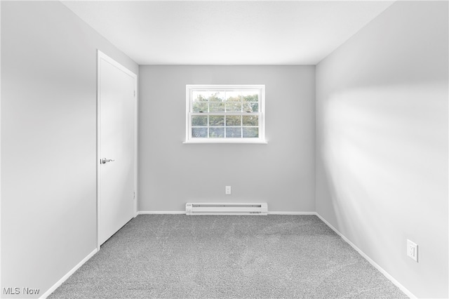 carpeted spare room with a baseboard heating unit