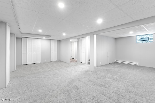 basement featuring a baseboard heating unit, light carpet, and a paneled ceiling