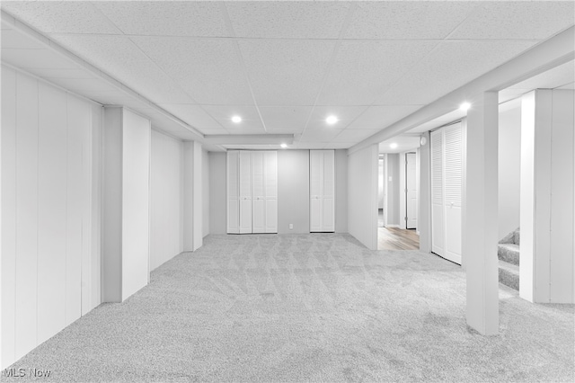 basement featuring light carpet and a paneled ceiling