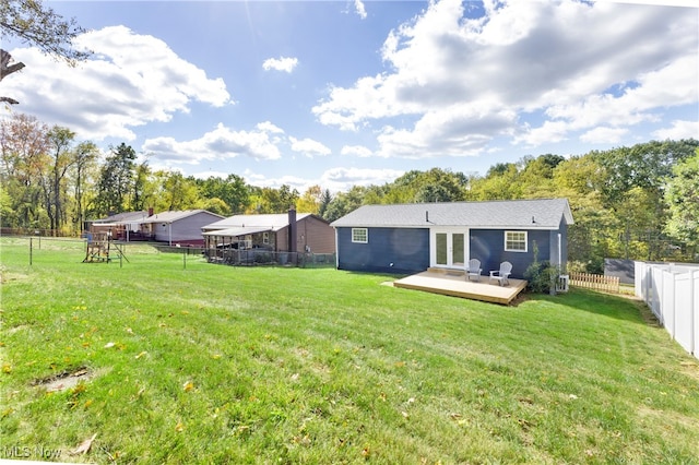 back of house with a yard, a wooden deck, and a playground