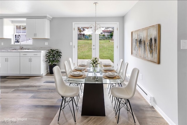 dining area featuring baseboard heating, a healthy amount of sunlight, sink, and light wood-type flooring