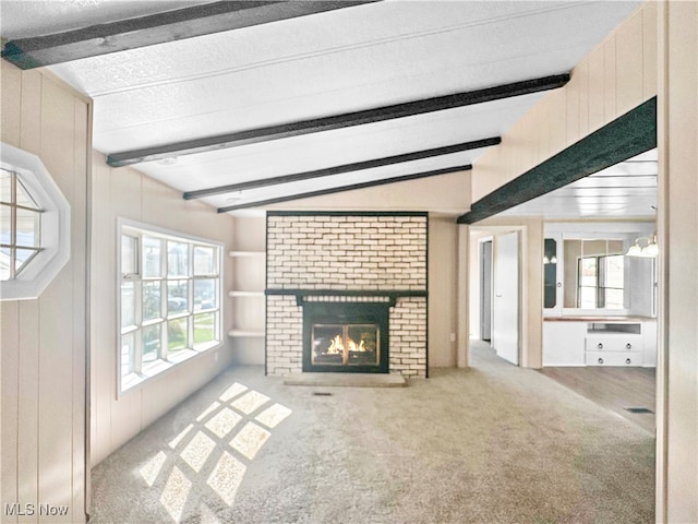 unfurnished living room with carpet floors, vaulted ceiling with beams, wooden walls, and a fireplace