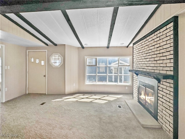 unfurnished living room featuring a fireplace, carpet, lofted ceiling with beams, and a textured ceiling