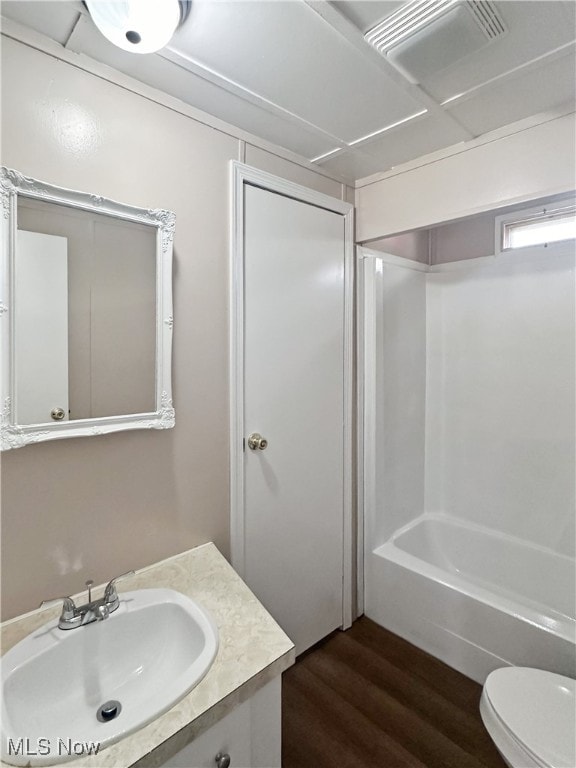 full bathroom featuring hardwood / wood-style floors, vanity, shower / tub combination, and toilet