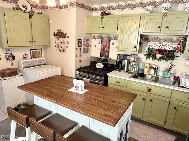 kitchen with green cabinetry, stainless steel range with gas stovetop, and sink