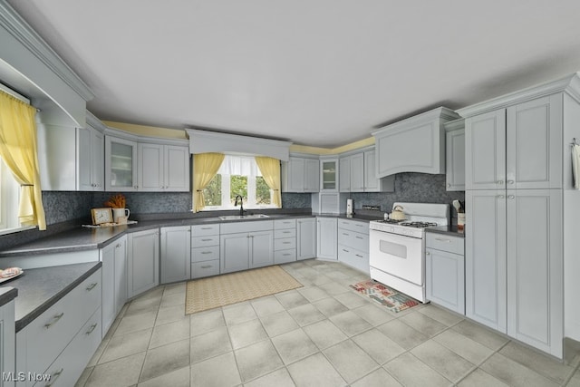 kitchen with white gas stove, sink, light tile patterned floors, and gray cabinetry