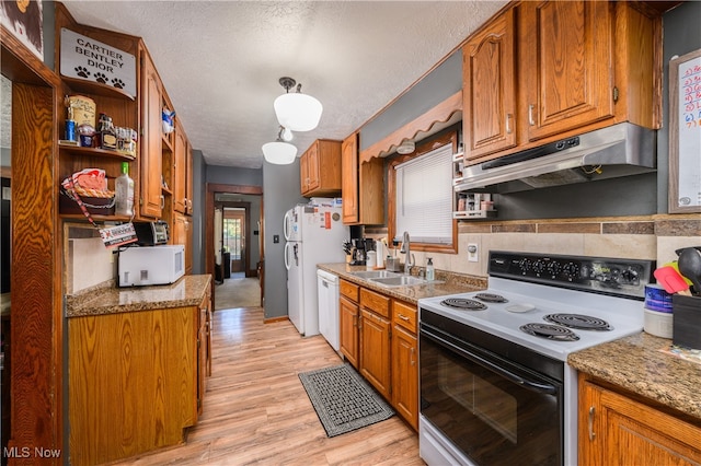 kitchen featuring light wood-type flooring, light stone counters, white appliances, sink, and a textured ceiling