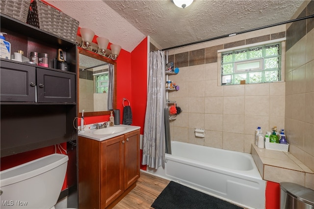 full bathroom with a healthy amount of sunlight, hardwood / wood-style flooring, a textured ceiling, and toilet