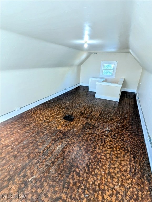 bonus room with dark carpet and vaulted ceiling