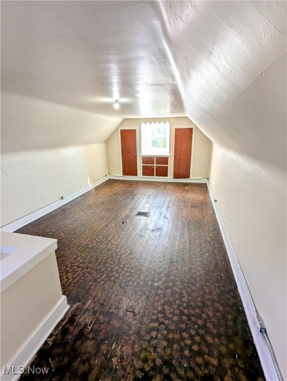 additional living space featuring lofted ceiling and dark hardwood / wood-style floors