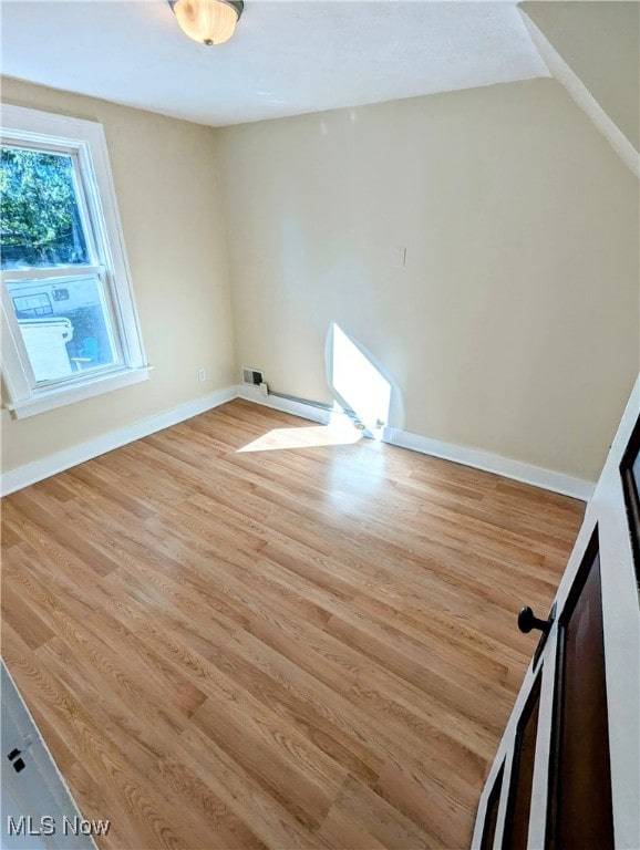 spare room featuring vaulted ceiling and light hardwood / wood-style flooring