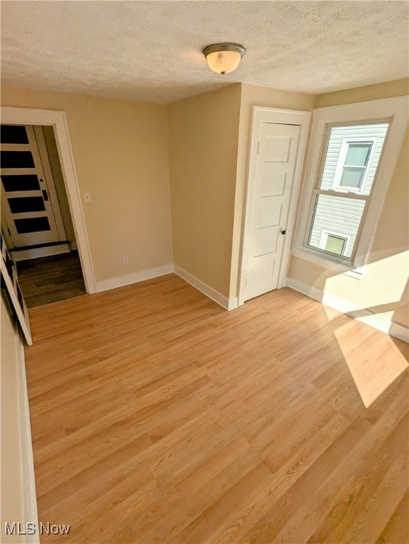 empty room featuring a textured ceiling and light hardwood / wood-style flooring