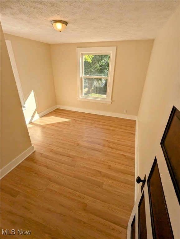 unfurnished room featuring a textured ceiling and light wood-type flooring