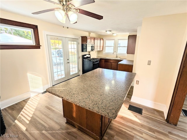 kitchen featuring french doors, a center island, gas stove, and light hardwood / wood-style floors