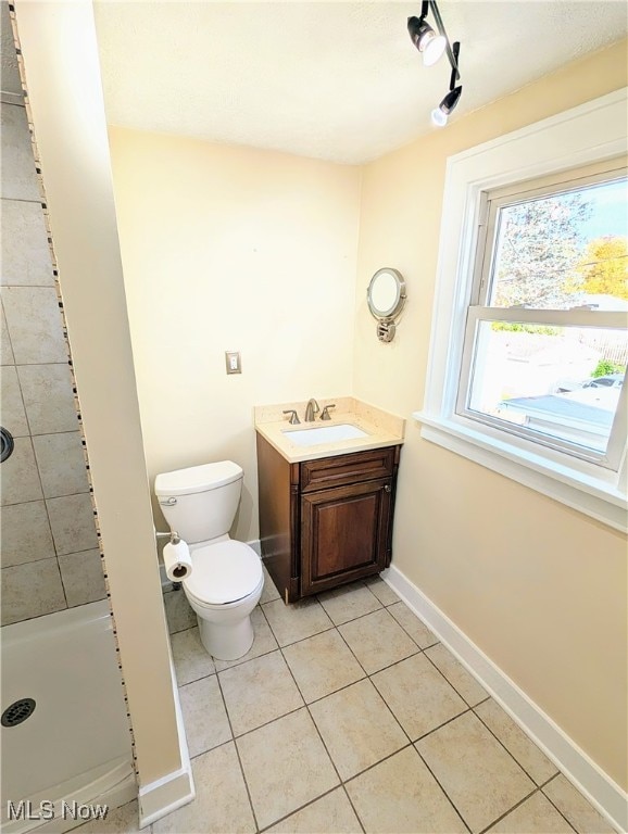 bathroom featuring a tile shower, toilet, tile patterned flooring, and vanity