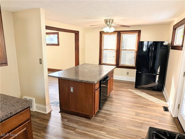 kitchen featuring light hardwood / wood-style floors, a healthy amount of sunlight, black appliances, and a kitchen island