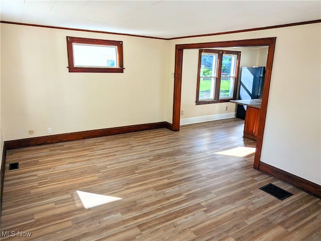 spare room with light hardwood / wood-style floors and crown molding