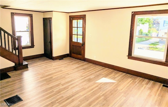 entryway with light hardwood / wood-style floors, ornamental molding, and plenty of natural light